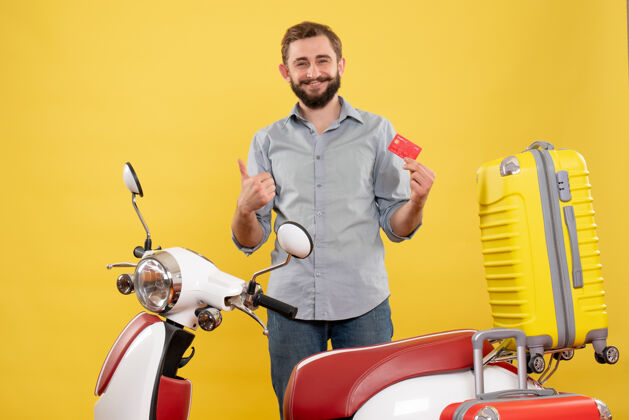 摩托车带着微笑的年轻人站在摩托车后面 背着手提箱 在黄色上做着“ok”的手势品牌微笑手提箱