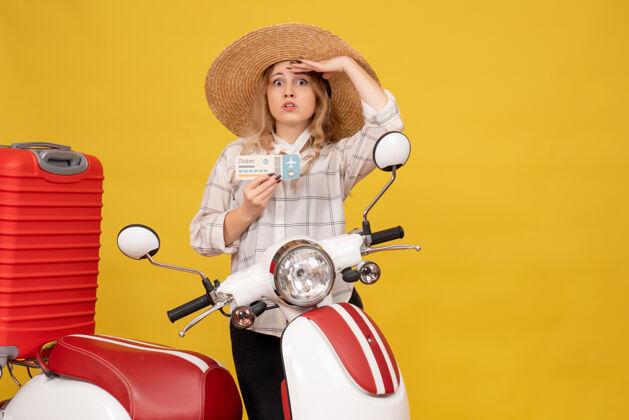 收集一个戴着帽子的专注的年轻女子坐在摩托车上拿着行李 拿着车票仔细地看着什么东西车辆成人行李