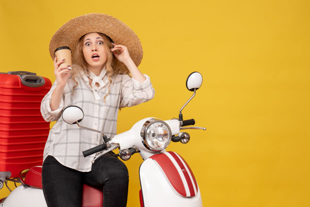 轮廓顶视图震惊的年轻女子戴着帽子 坐在摩托车上 拿着咖啡帽子高尔夫顶
