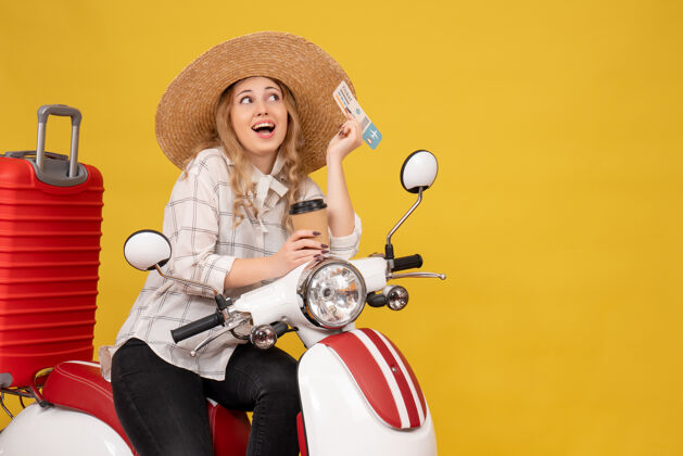 咖啡戴着帽子 坐在摩托车上 拿着咖啡和黄色的车票 微笑着 充满梦想的年轻女子年轻女子摩托车传送带