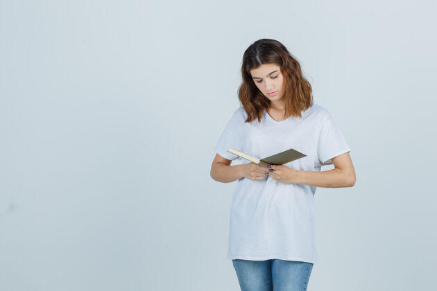 健康年轻女士一边看书 一边穿着t恤衫 牛仔裤 神情专注前视图水疗皮肤护理新鲜