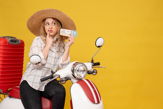高尔夫顶视图是一个戴着帽子坐在摩托车上拿着黄色车票的惊讶的年轻女子举行年轻女子摩托车