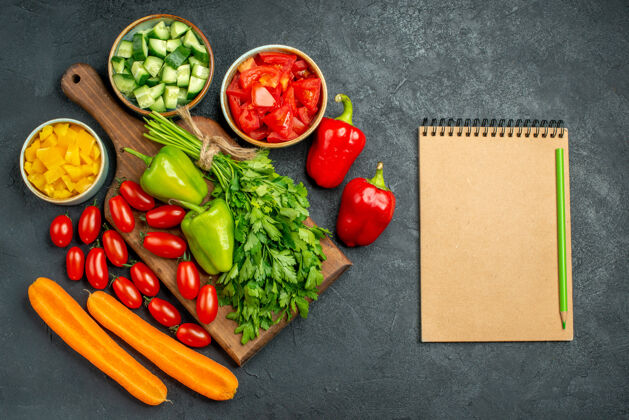 沙拉盘子架的顶视图 上面和旁边是蔬菜 旁边是深灰色背景的记事本蔬菜新鲜背景
