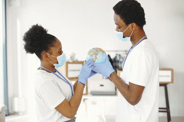 多样性手里拿着地球仪戴着防护面具和手套非洲人男女朋友流行病医学世界