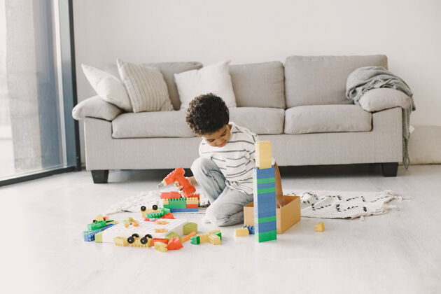 沙发孩子在地板上玩游戏非洲孩子组成一个构造器男孩的卷发游戏休闲非洲