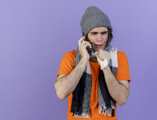 说话咳嗽的年轻病患戴着冬天的帽子和围巾在电话上讲话 紫色背景下孤立咳嗽年轻电话