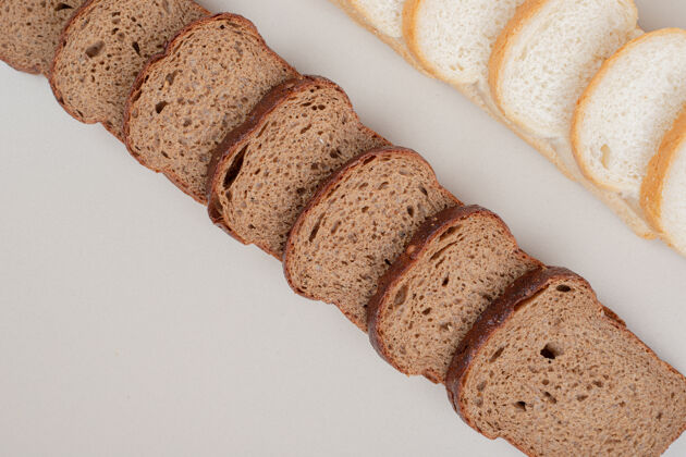 切把新鲜的白面包和棕色面包切片放在白色的表面上硬皮面包切片
