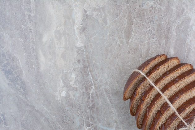 面包房用绳子把棕色面包片放在大理石表面切面包谷物