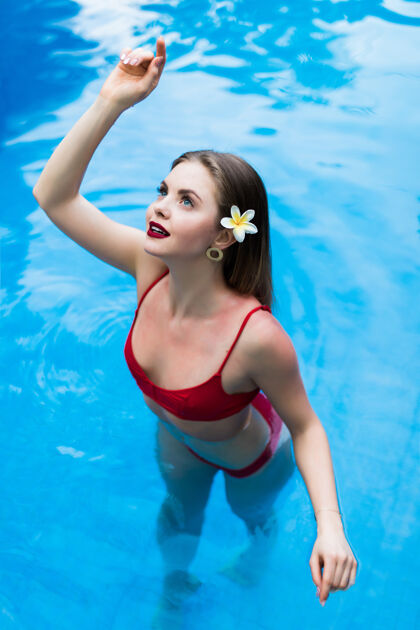 性感优雅性感的女人穿着红色比基尼在阳光下晒得苗条匀称的游泳池游泳多彩皮肤成人