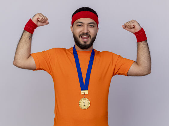 腕带自信的年轻运动男子戴着头带和腕带与奖牌显示强烈的姿态隔离在白色背景自信年轻运动