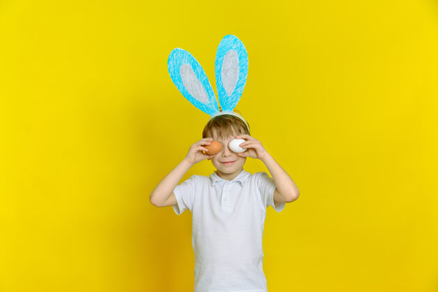 耳朵快乐的小男孩 带着复活节彩蛋和兔子耳朵节日微笑鸡蛋