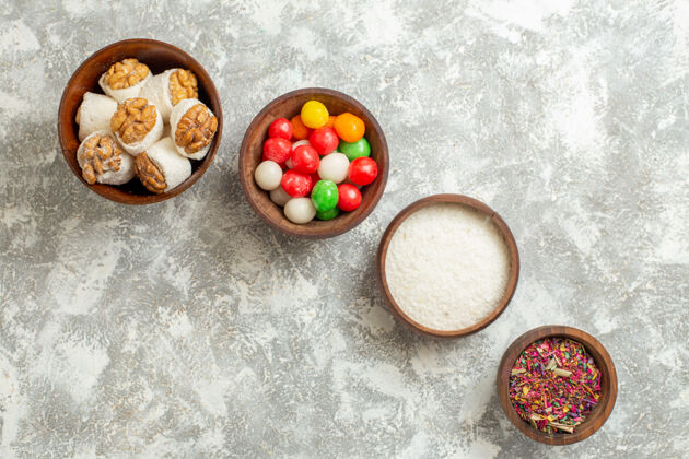 自封俯瞰彩色糖果与坚果围在一个白色的表彩色糖果彩虹糖果晚餐蔬菜