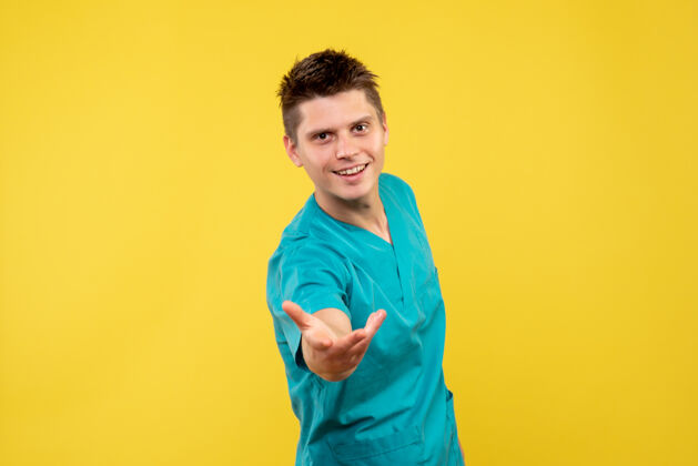 人黄色墙壁上穿着医疗服的男医生的正视图快乐西装成人