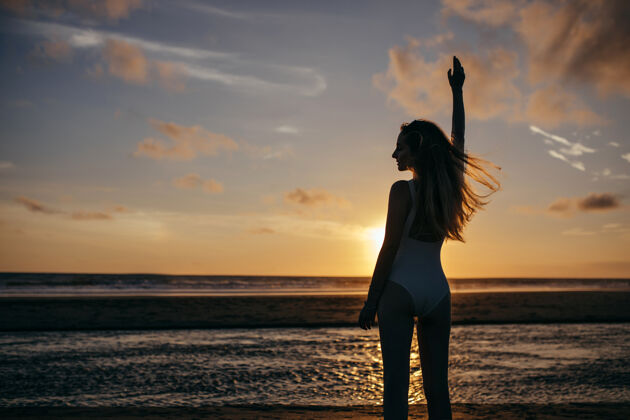 灵感白种女人在度假时穿白色泳装无忧无虑的年轻女士在海边享受夜晚 看着美丽的日落太阳肖像地平线