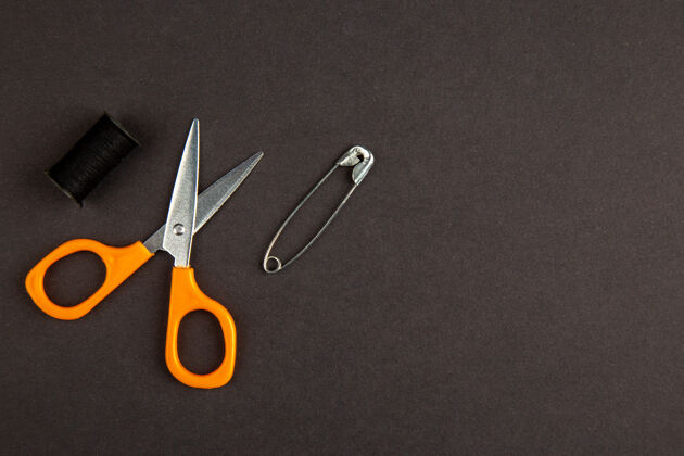 工具顶视图橙色剪刀在黑暗的背景银切割夹子