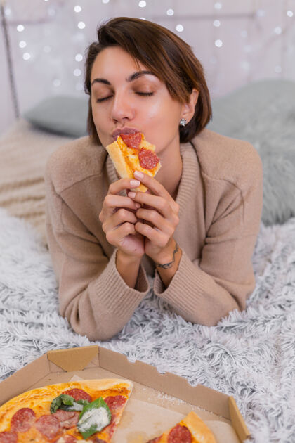 饿女东从家里卧室的床上送快餐女东独自享用肥肉食品 披萨放松卧室女士
