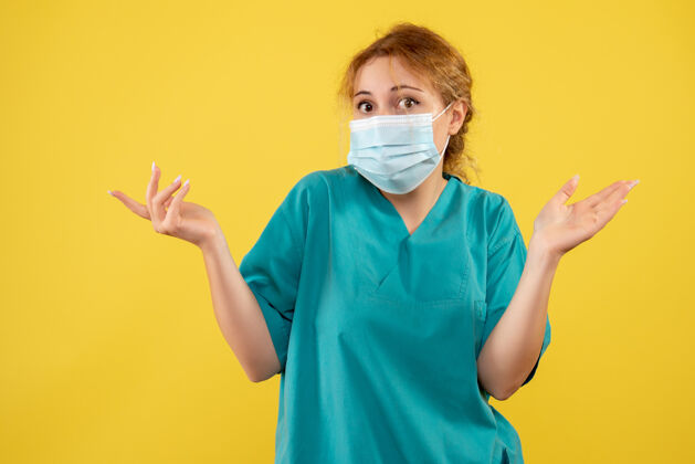 肖像黄墙上年轻女医生穿着医疗服 戴着口罩的正面图成人医院面部