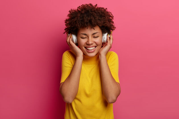 积极面带微笑的黑皮肤女人喜欢旋律 触摸耳机科技肖像轨道