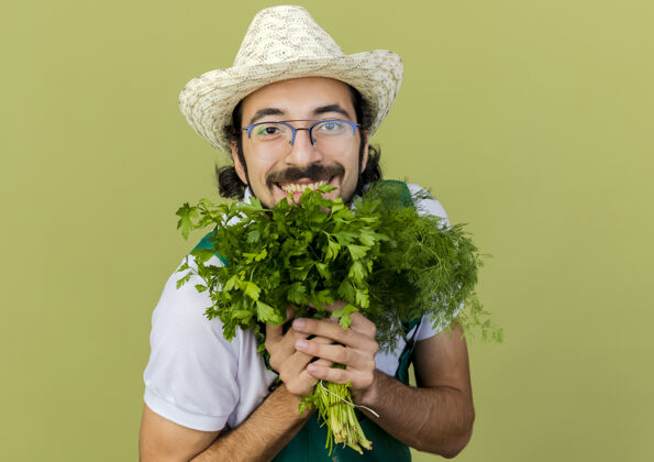 举行快乐的男园丁戴着眼镜 戴着园艺帽 手里拿着茴香和香菜空间园艺光学
