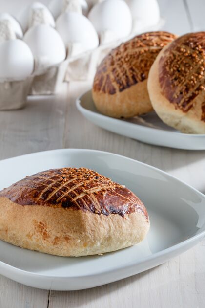面包房垂直特写镜头新鲜出炉的面包在一个白色的盘子在一个木桌上早餐美味新鲜