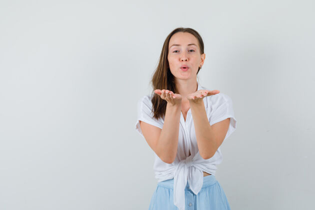 清洁一个年轻的女人穿着白衬衫和淡蓝色的裙子在前面接吻 看起来很开心黑发衬衫模特