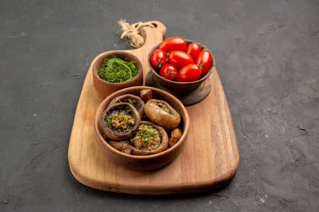 盘子前视图美味的熟蘑菇和西红柿放在深灰色的桌子上野生熟食肉碗健康