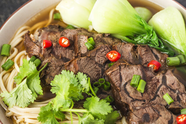 牛肉麻辣红汤牛肉面放在木桌上的碗里美味午餐蔬菜