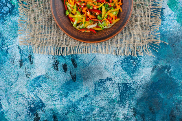 盘子蔬菜沙拉放在盘子里的粗麻布上 蓝色背景粗麻布新鲜美味