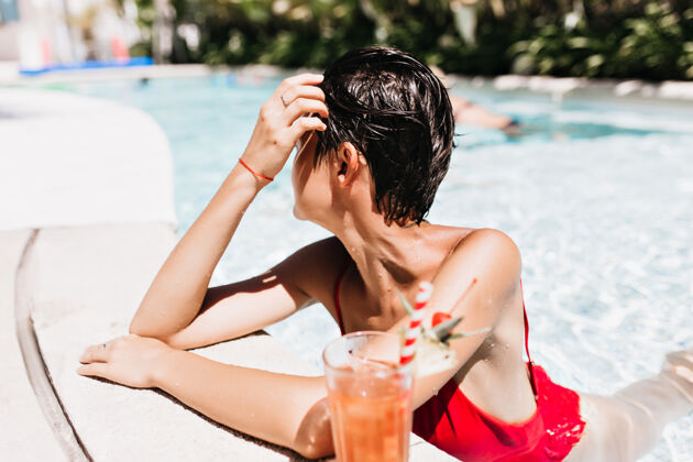 休息一个短发女人在温暖的日子里游泳时把目光移开了泳装游泳池大笑