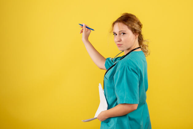 女医生黄墙上穿着医疗服的女医生手持分析图抱健康西装