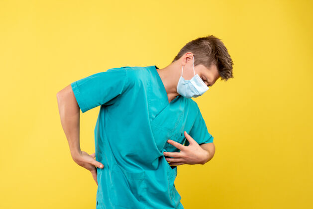 疼痛黄墙上 男医生穿着医疗服 戴着无菌口罩 痛苦不堪成人病毒人