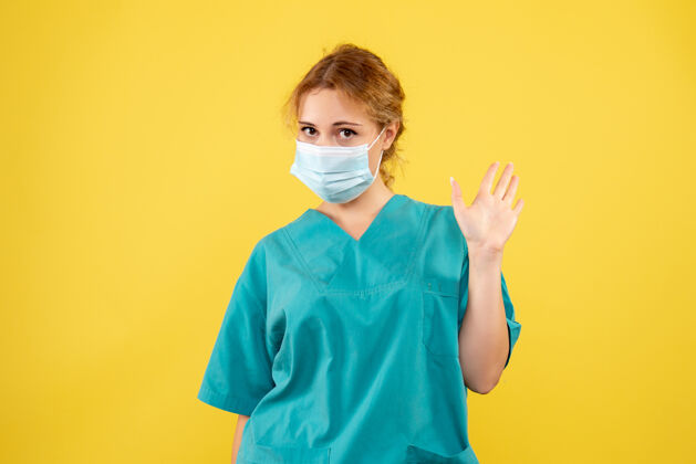 快乐黄墙上穿着医疗服 戴着无菌口罩的女医生的正面图护士正面脸