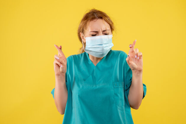 健康黄墙上年轻的女医生穿着医疗服 戴着口罩护士人正面