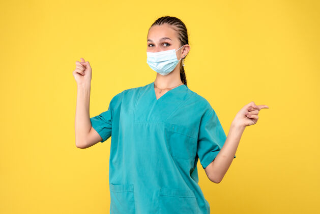 面具黄墙上穿着医疗服 戴着无菌口罩的女医生的正面图脸大流行护士