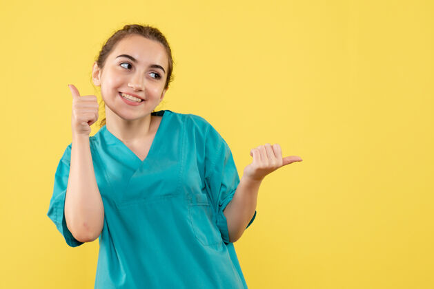 成人黄色墙壁上穿着医疗服的年轻女医生的正视图正面情绪套装