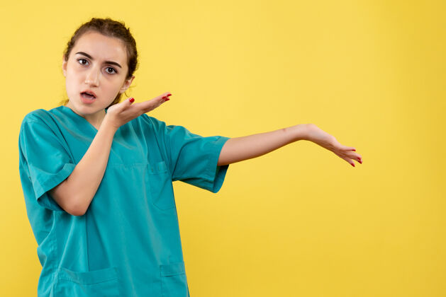 情绪黄色墙壁上穿着医疗服的年轻女医生的正视图成人快乐舞蹈