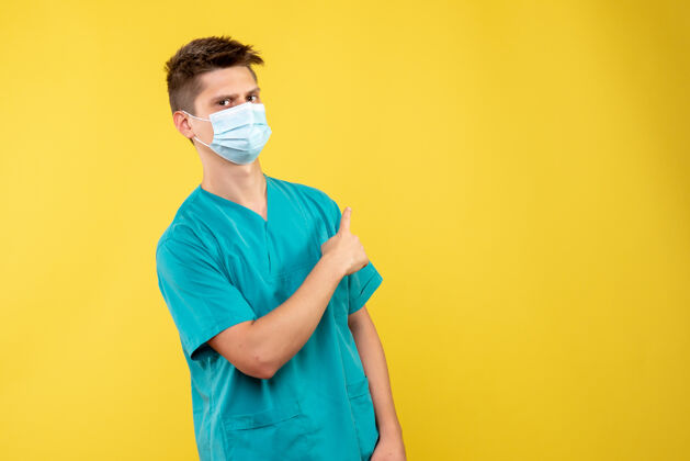 肖像黄墙上的男医生穿着医疗服 戴着无菌口罩绝育医院人
