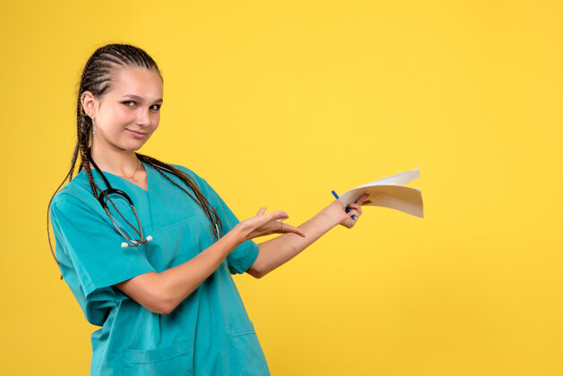 病毒身着医疗服的女医生的正面图 黄色的墙上有纸人药听诊器