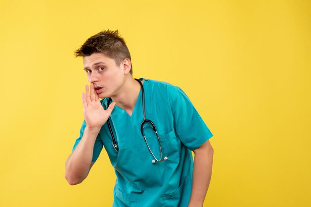 人黄色墙壁上穿着医疗服 带听诊器的男医生的正视图病毒情绪正面