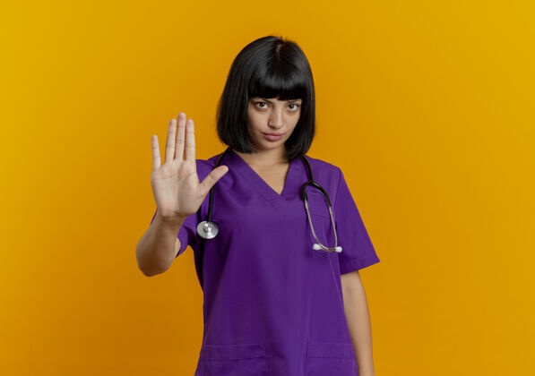 制服自信的年轻黑发女医生穿着制服 带着听诊器手势停止手势信心手黑发