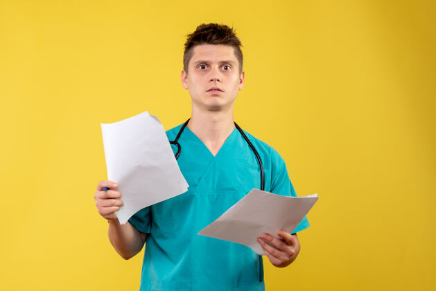 男医生黄色墙壁上穿着医疗服的男医生的前视图和分析分析医学快乐