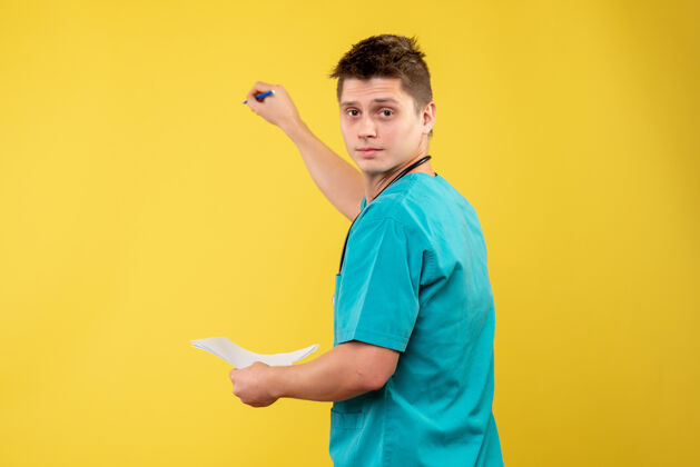 快乐黄色墙壁上的男医生穿着医疗服的正面图情绪健康男性医生