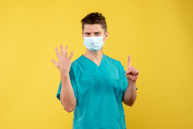 正面黄墙上的男医生穿着医疗服 戴着无菌口罩微笑面具套装