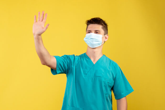 病毒身穿医疗服的男医生正面图 黄色墙上有无菌面罩男性人人