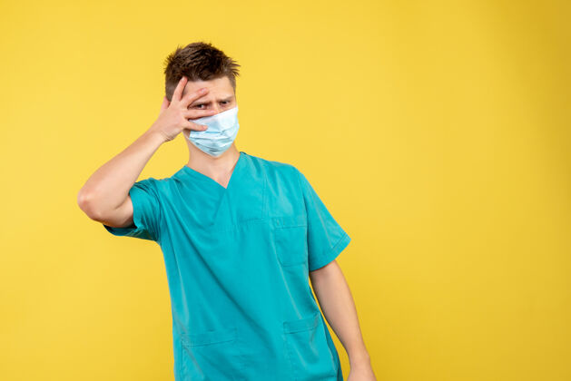男性医生黄墙上的男医生穿着医疗服 戴着无菌口罩人健康医院