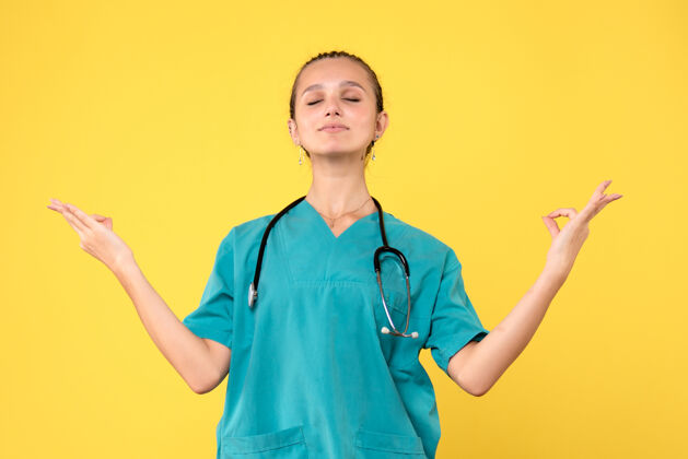 肖像身着医疗服的女医生在黄墙上冥想的正面图护士正面微笑