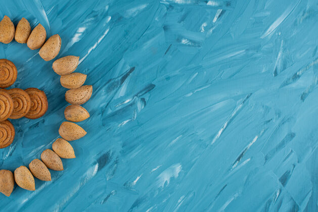 黄色一圈杏仁和新鲜甜甜的圆形饼干 背景是蓝色的生的杏仁健康
