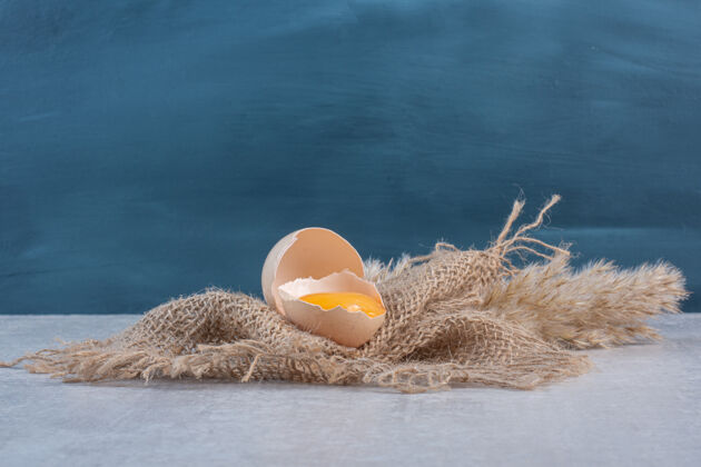 农产品蛋黄在一块破壳上放在一块布上放在大理石桌上美味蛋黄鸡蛋