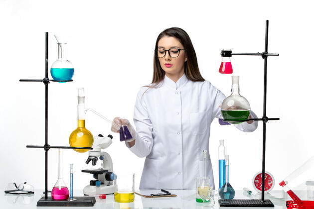 疾病正面图：穿着无菌医疗服的女化学家站在桌子旁 拿着浅白背景病毒疾病的解决方案-大流行科学立场医学周围