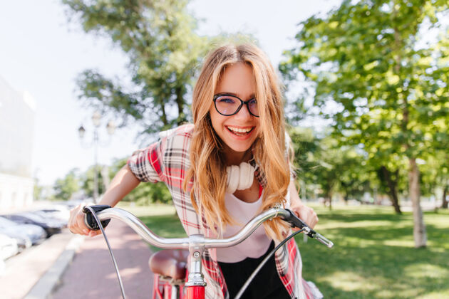 快乐悠闲的长发女孩戴着耳机骑在自行车上美丽的女士带着可爱的微笑坐在自行车上城市乐趣可爱